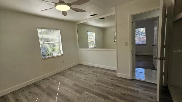 an empty room with wooden floor and windows