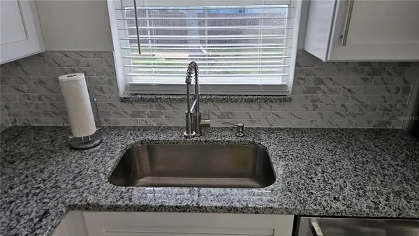 a kitchen with granite countertop a sink and a stove
