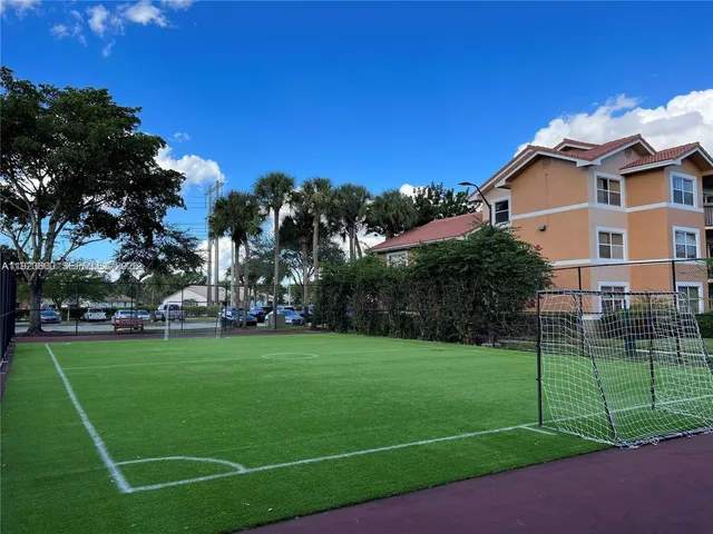 a view of a white house with a big yard plants and large trees