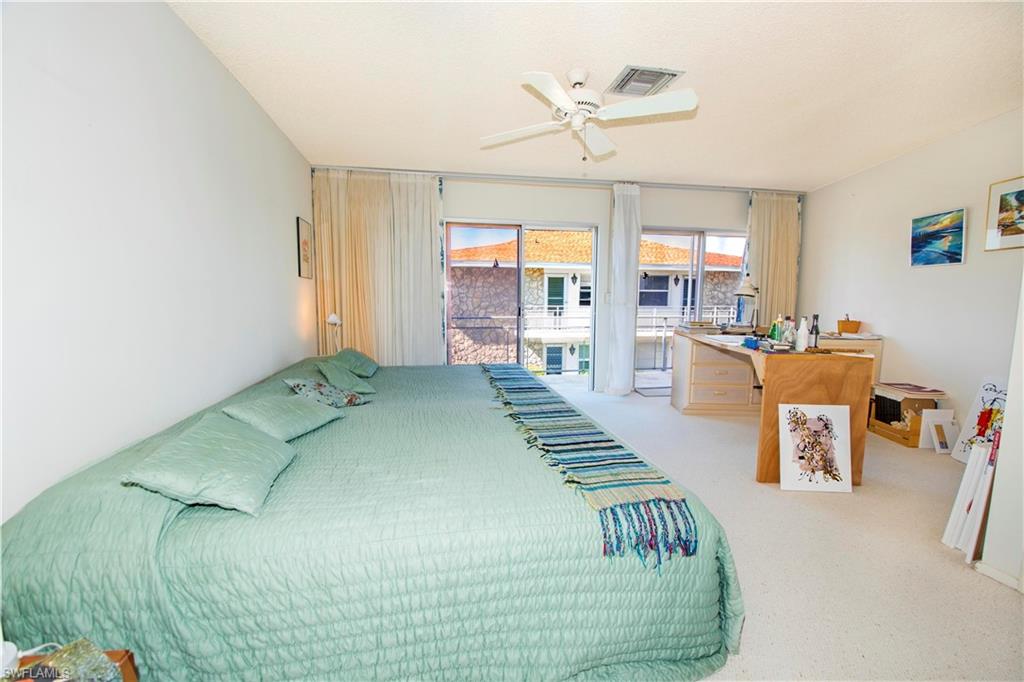 330 Kon Tiki Drive, Unit A2 Naples, FL 34113 - Photo 9 of 19 a bedroom with furniture and a chandelier