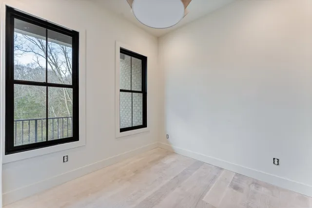 a view of a hallway with wooden floor and a bathroom