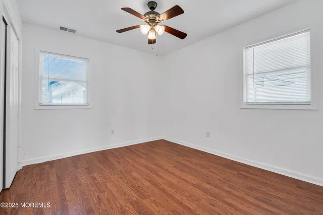 a view of an empty room with window and wooden floor