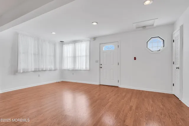 a view of an empty room with wooden floor and window