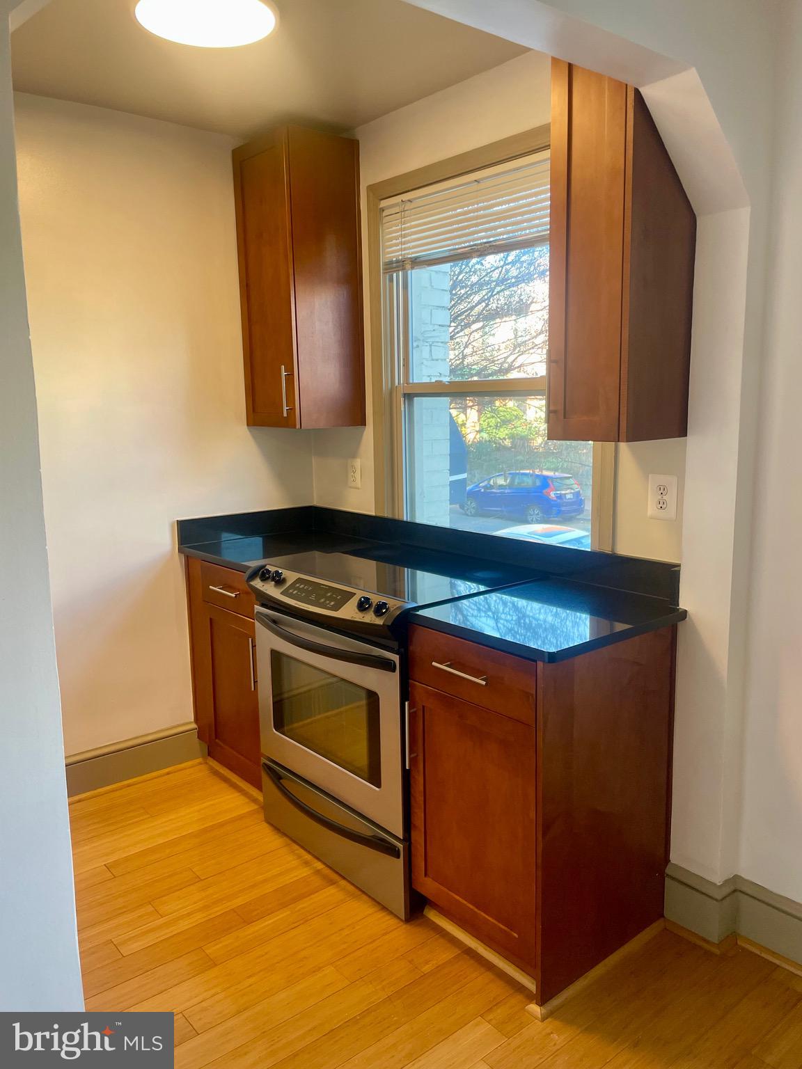 1363 K Street Southeast, Unit 103 Washington, DC 20003 - Photo 4 of 14 a kitchen with granite countertop a stove a sink and a microwave oven next to a window