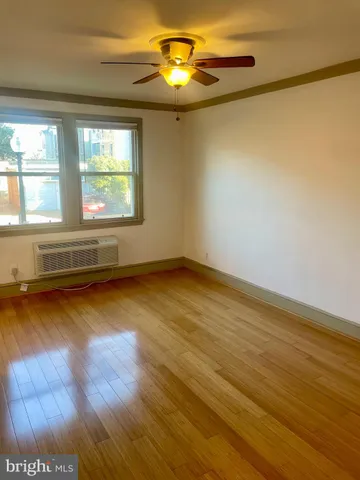 a view of an empty room with window and wooden floor