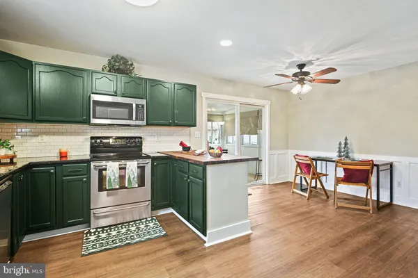 a kitchen with kitchen island granite countertop a stove top oven a sink dishwasher a dining table and chair with wooden floor
