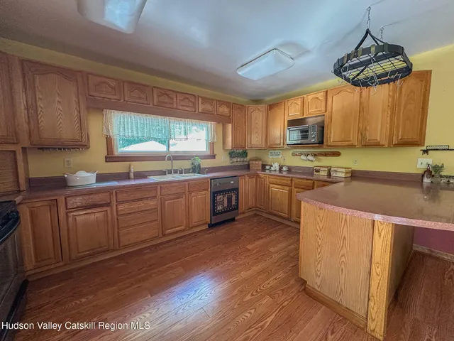 a kitchen with stainless steel appliances granite countertop wooden cabinets a sink a stove a refrigerator and island