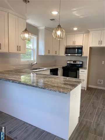 a kitchen with kitchen island granite countertop stainless steel appliances a large counter space a sink and cabinets