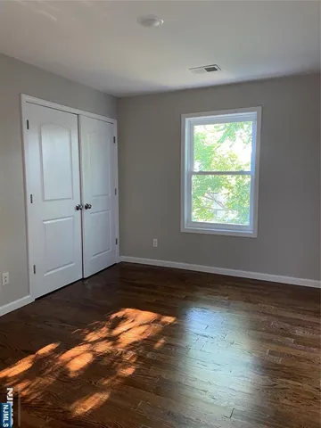 an empty room with wooden floor closet and windows