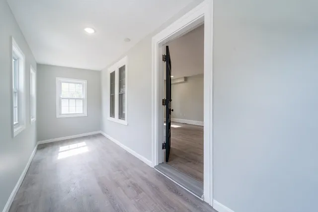 an empty room with wooden floor mirror and windows