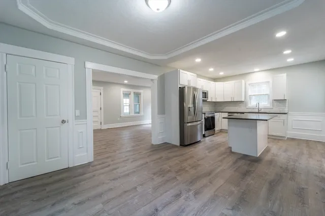 a kitchen with stainless steel appliances granite countertop a refrigerator a sink dishwasher and a oven with white cabinets