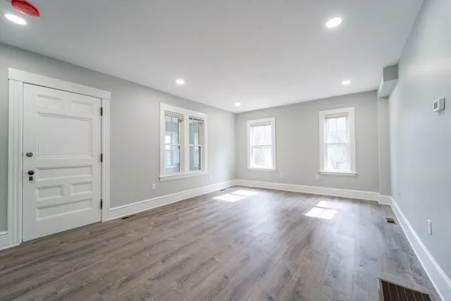 a view of an empty room with wooden floor and windows
