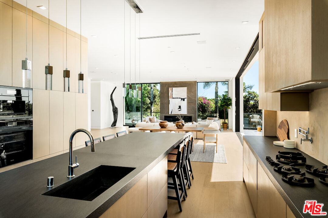 5931 Kanan Dume Road Malibu, CA 90265 - Photo 21 of 53 a kitchen with stainless steel appliances a stove sink and white cabinets with wooden floor