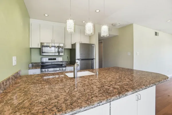 a kitchen with kitchen island granite countertop a sink cabinets and stainless steel appliances