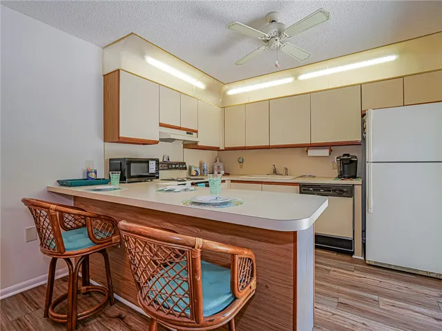 a kitchen with stainless steel appliances granite countertop a sink a stove a refrigerator and island with wooden floor