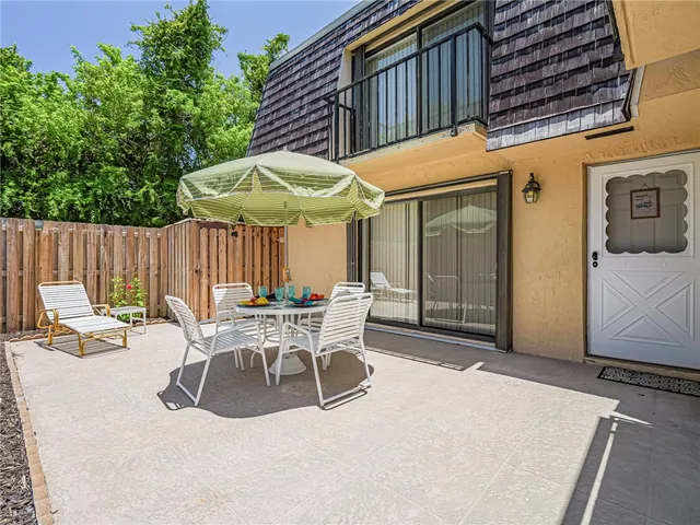 a view of a patio with table and chairs under an umbrella with a small yard