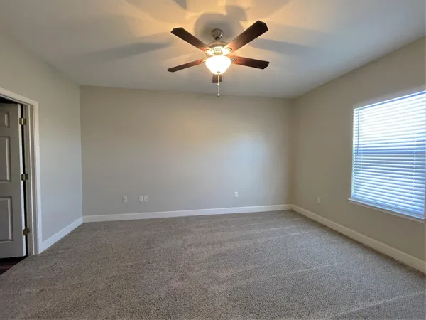 an empty room with window and ceiling fan