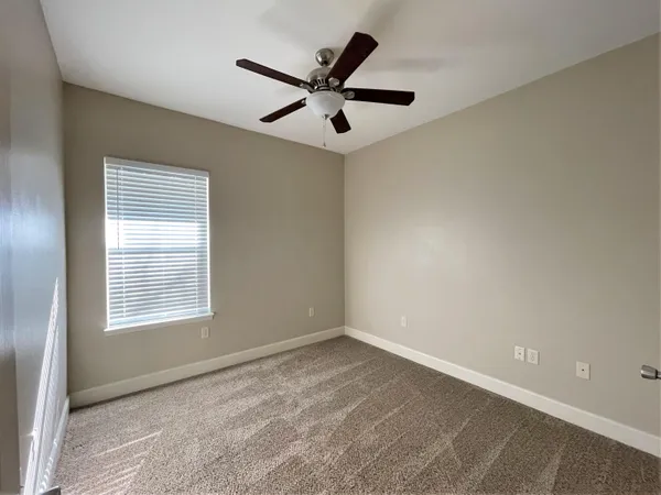 a view of an empty room with a ceiling fan and window