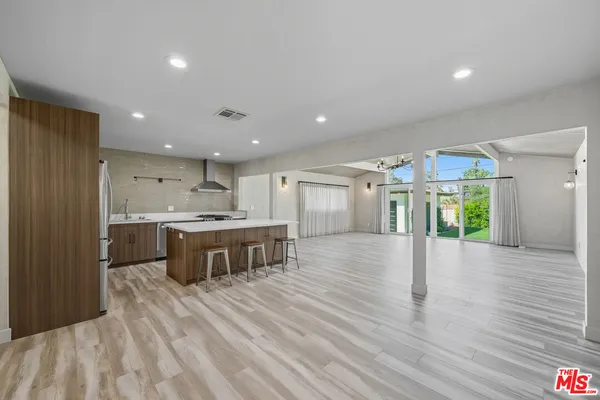 a large kitchen with a large counter top a sink stainless steel appliances and cabinets