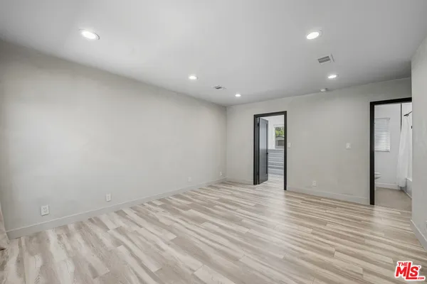 a view of an empty room with wooden floor and closet