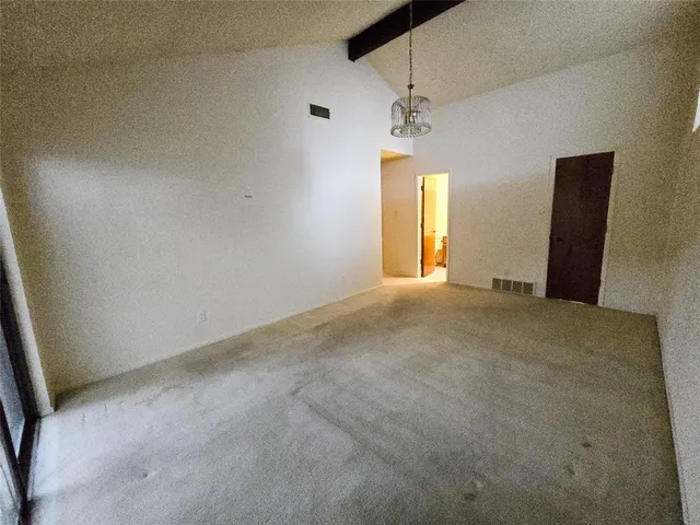 an empty room with a chandelier fan and windows