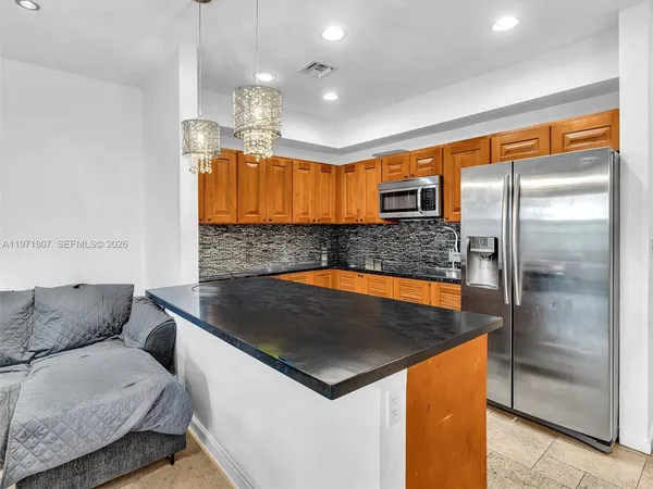 a kitchen with stainless steel appliances granite countertop a sink a refrigerator and a granite counter tops