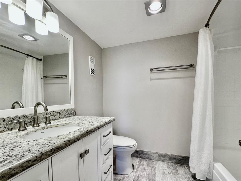 5301 Northwest 2nd Avenue, Unit 408 Boca Raton, FL 33487 - Photo 20 of 32 a bathroom with a granite countertop sink a toilet and a mirror