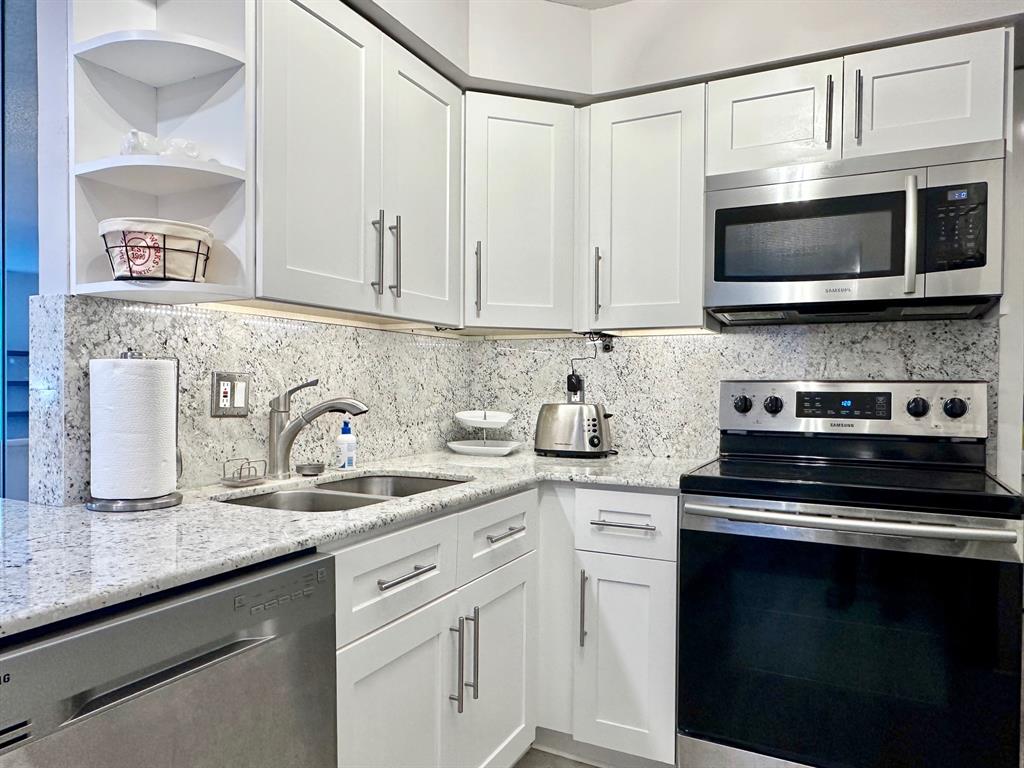5301 Northwest 2nd Avenue, Unit 408 Boca Raton, FL 33487 - Photo 3 of 32 a kitchen with granite countertop white cabinets and stainless steel appliances