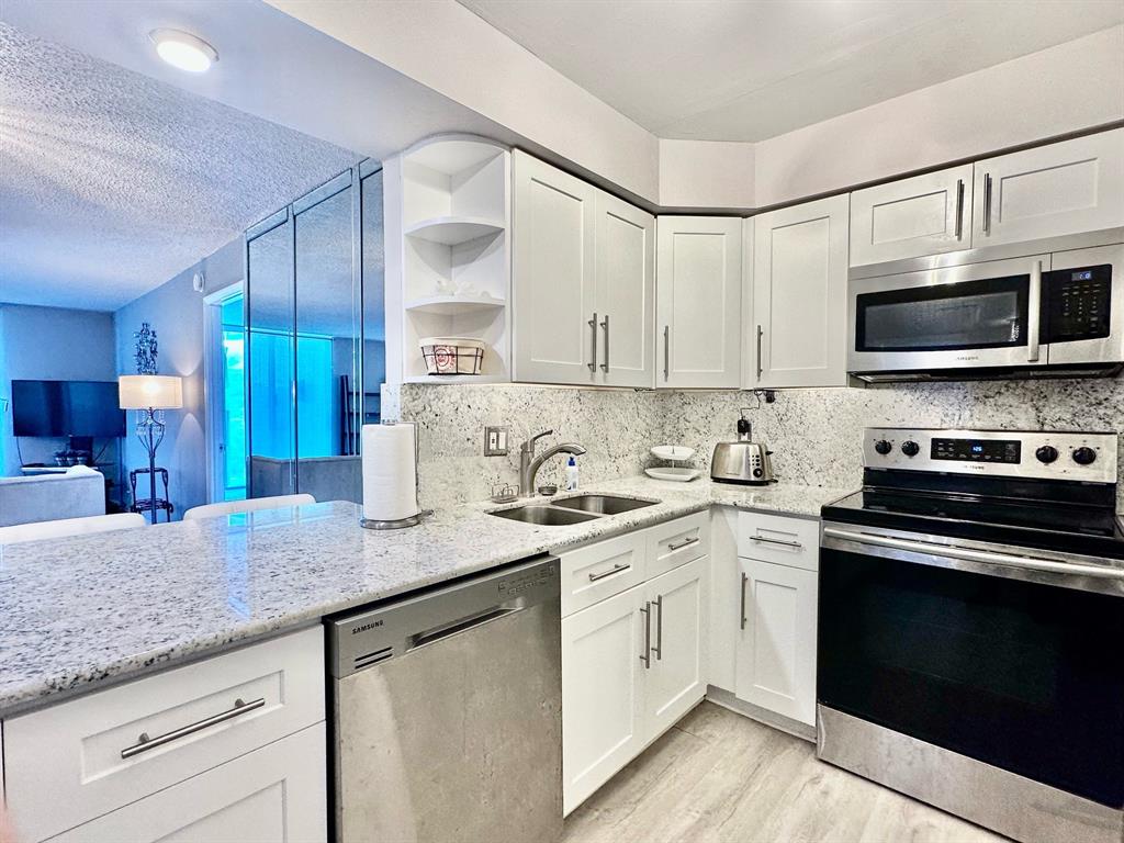 5301 Northwest 2nd Avenue, Unit 408 Boca Raton, FL 33487 - Photo 4 of 32 a kitchen with stainless steel appliances granite countertop a sink and cabinets