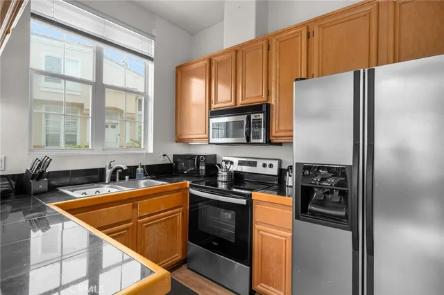 a kitchen with stainless steel appliances granite countertop a refrigerator a stove a sink and dishwasher
