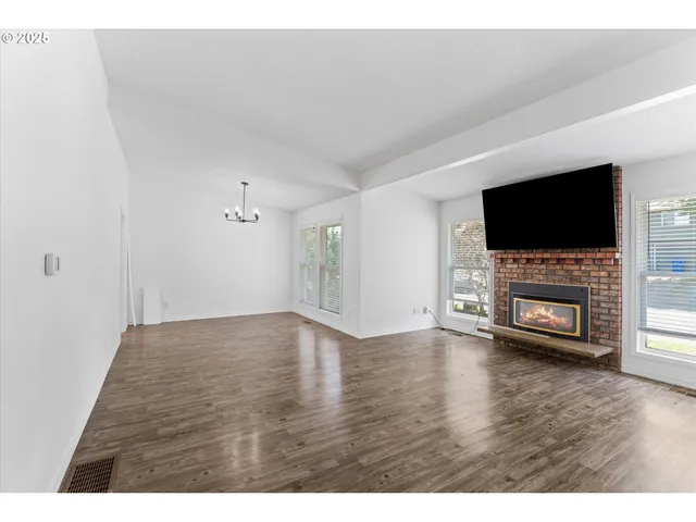 a view of a livingroom with a flat screen tv a fireplace and wooden floor