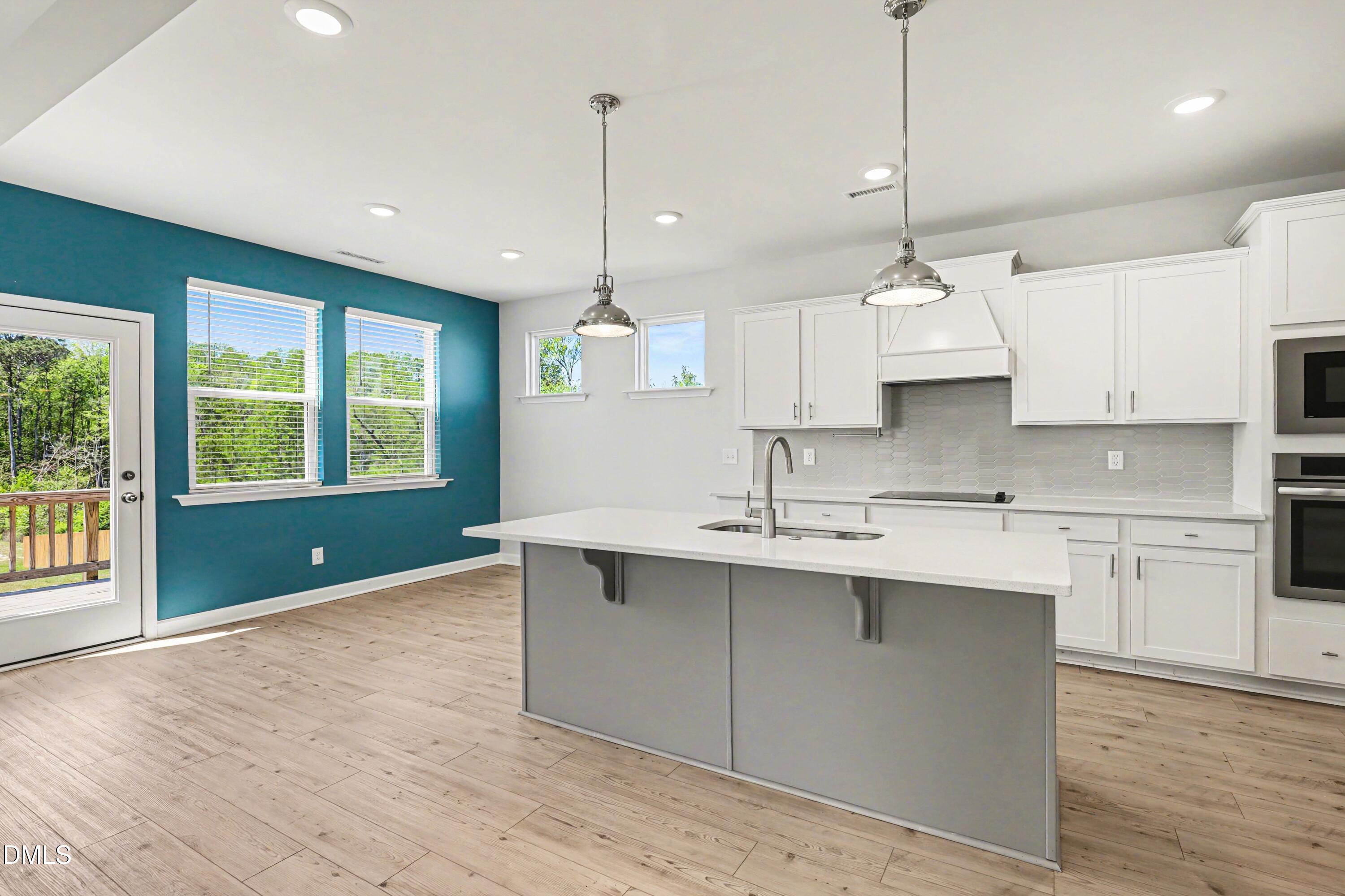 90 Rigsby Avenue Four Oaks, NC 27524 - Photo 14 of 43 a kitchen with kitchen island a sink stainless steel appliances and a wooden floor