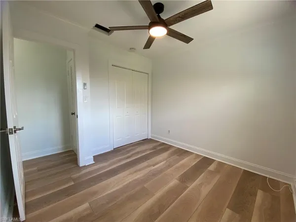 an empty room with wooden floor fan and windows