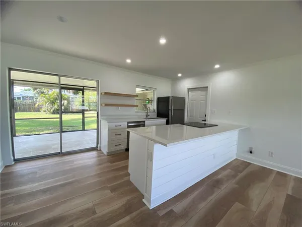 a view of kitchen with kitchen island wooden floor and living room
