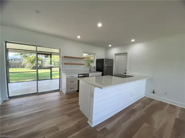 a view of kitchen with kitchen island wooden floor and living room