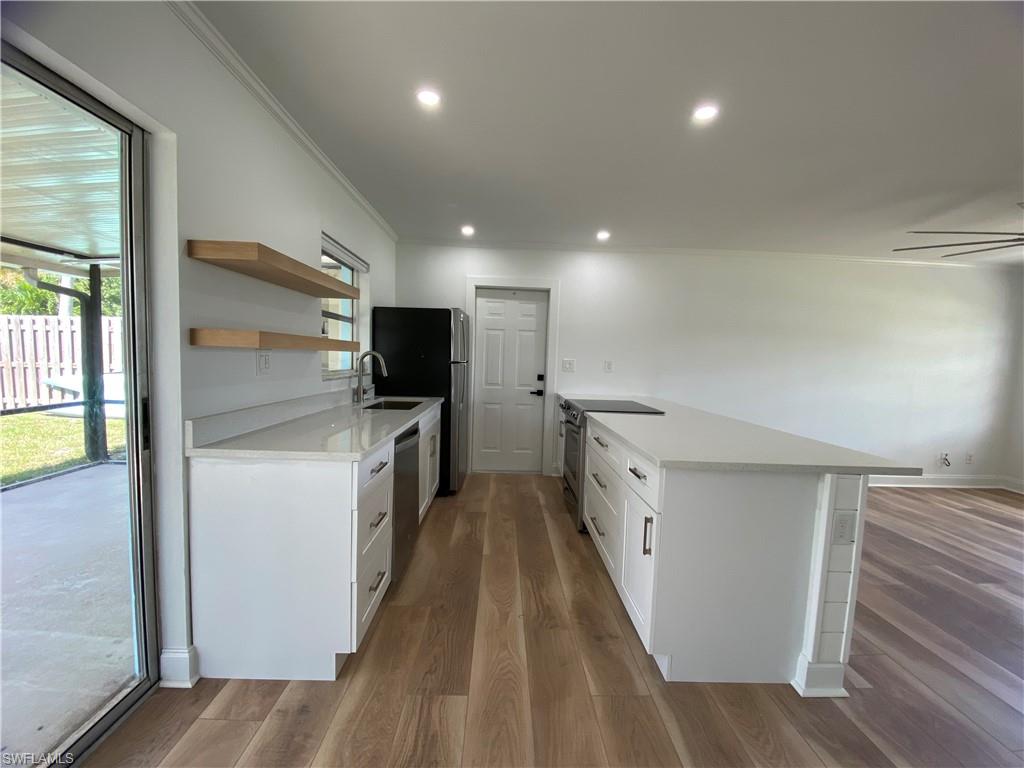 740 108th Avenue North Naples, FL 34108 - Photo 8 of 26 a view of a kitchen with a sink and dishwasher a refrigerator with wooden floor