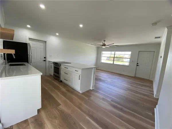 a kitchen with stainless steel appliances a stove top oven a sink dishwasher and a refrigerator with wooden floor