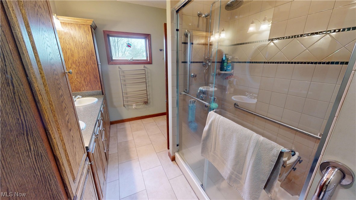 10323 Smith Road Litchfield, OH 44253 - Photo 24 of 50 Bathroom featuring radiator heating unit, vanity, baseboards, and a shower stall