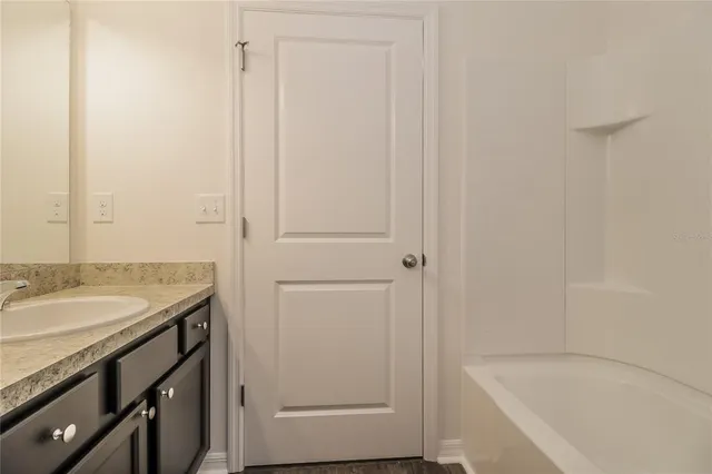 a bathroom with a granite countertop sink and a bathtub