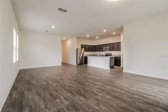 a view of kitchen with kitchen island a sink wooden floor and stainless steel appliances