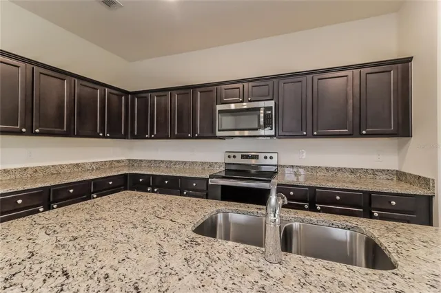 a kitchen with granite countertop a sink a stove a microwave and wooden cabinets