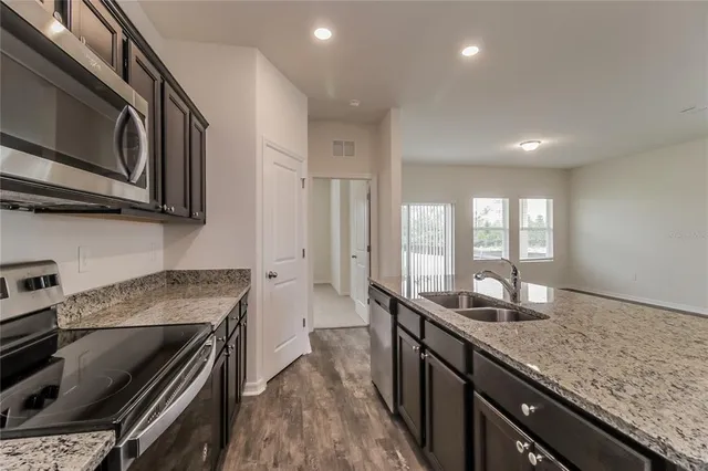 a kitchen with granite countertop kitchen island wooden cabinets stainless steel appliances a sink and a window