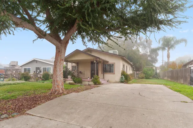 a front view of a house with a yard and large trees