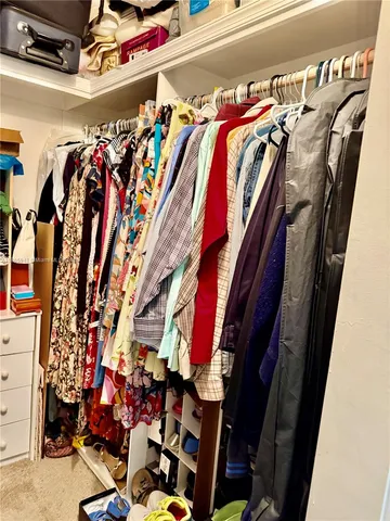 a view of walk in closet with clothes and shoes
