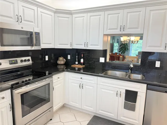 a kitchen with white cabinets and appliances