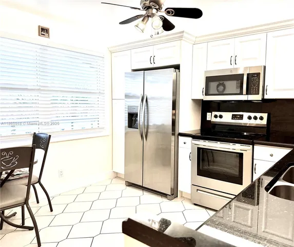 a kitchen with stainless steel appliances kitchen island granite countertop a refrigerator and a stove top oven