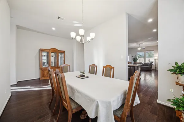 a kitchen with stainless steel appliances a stove top oven a sink dishwasher a refrigerator and a dining table with wooden floor