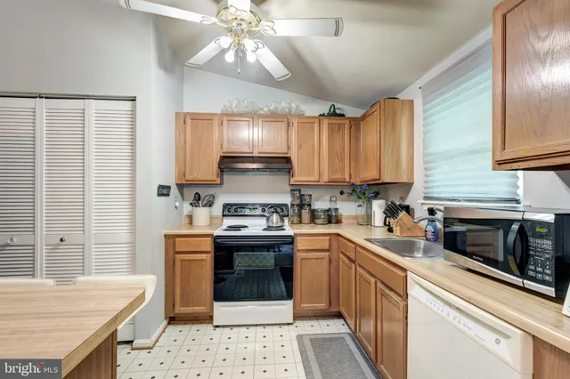a kitchen with stainless steel appliances kitchen island granite countertop a sink stove cabinets and refrigerator