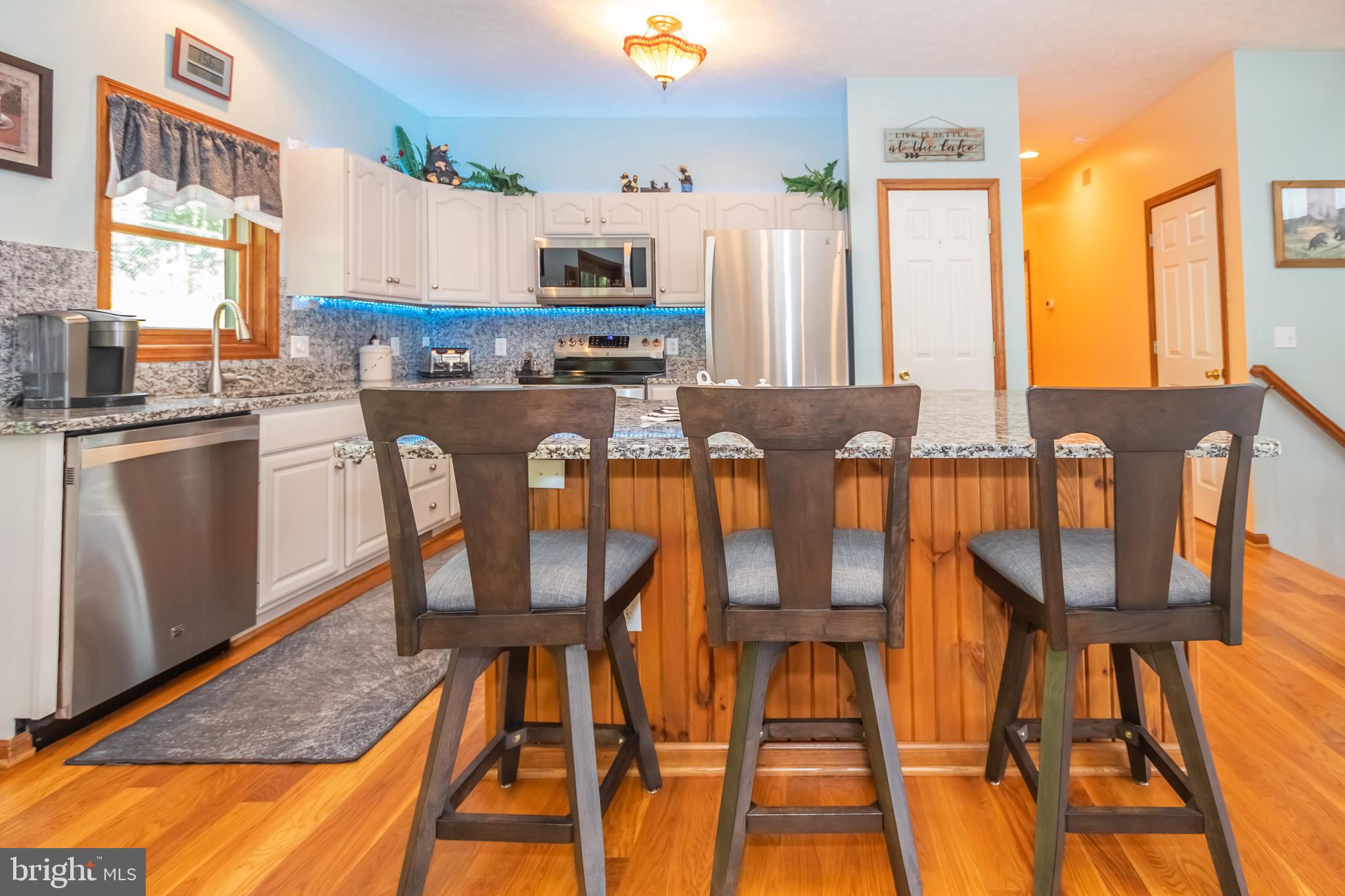 592 Marsh Hill Road McHenry, MD 21541 - Photo 7 of 51 a kitchen with stainless steel appliances granite countertop a stove top oven a sink a dining table and chairs with wooden floor