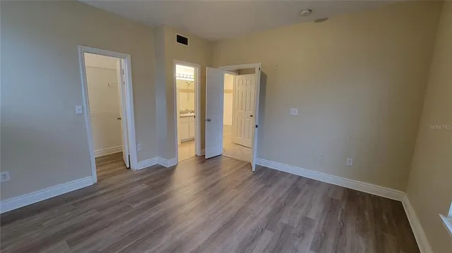 a view of an empty room with wooden floor and closet
